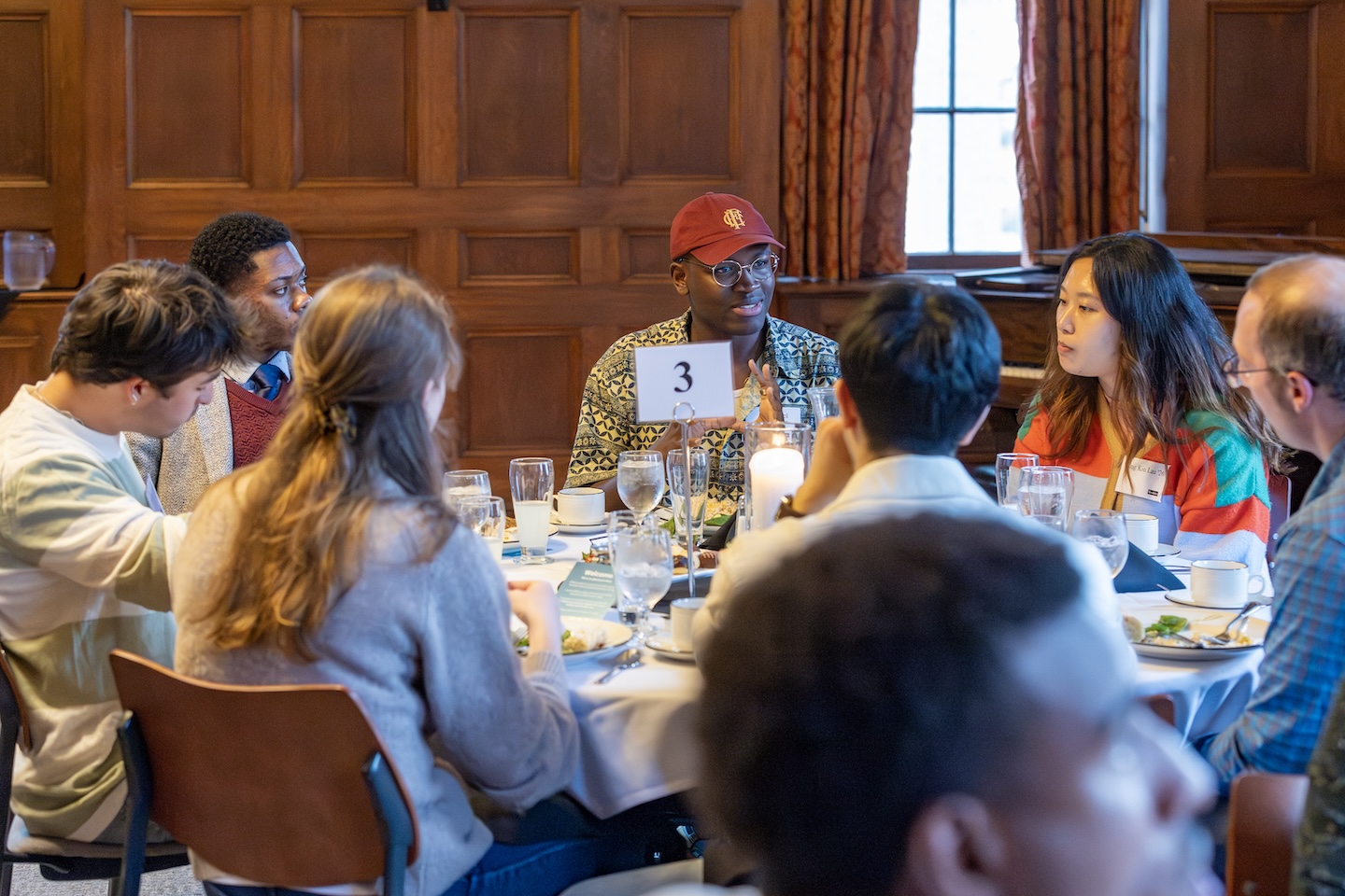 Alumni and students and faculty and staff sit around a dinner table and talk