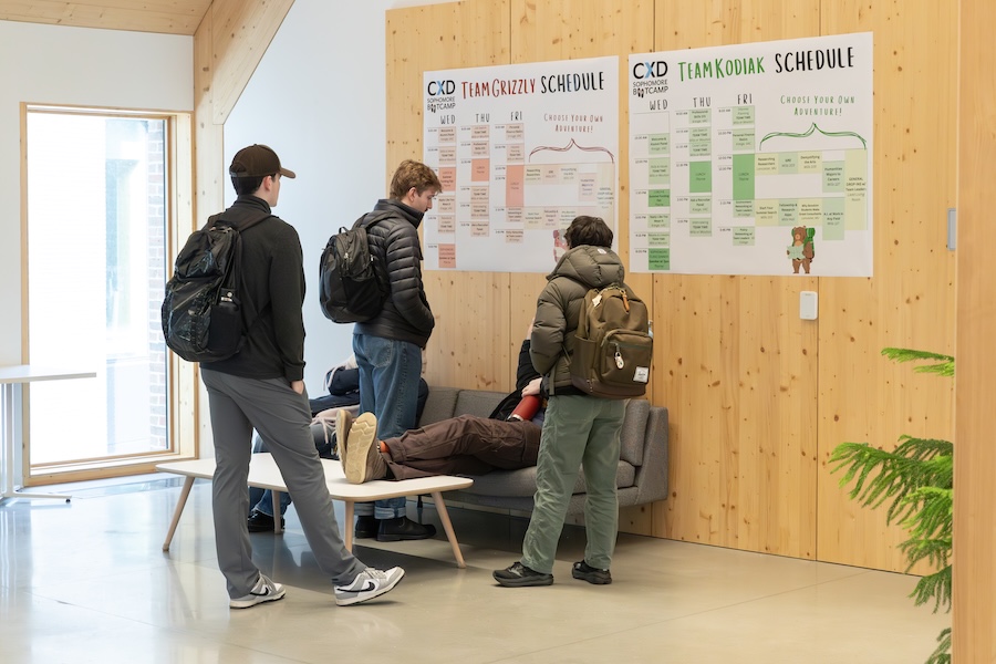 Students stand in front of a schedule