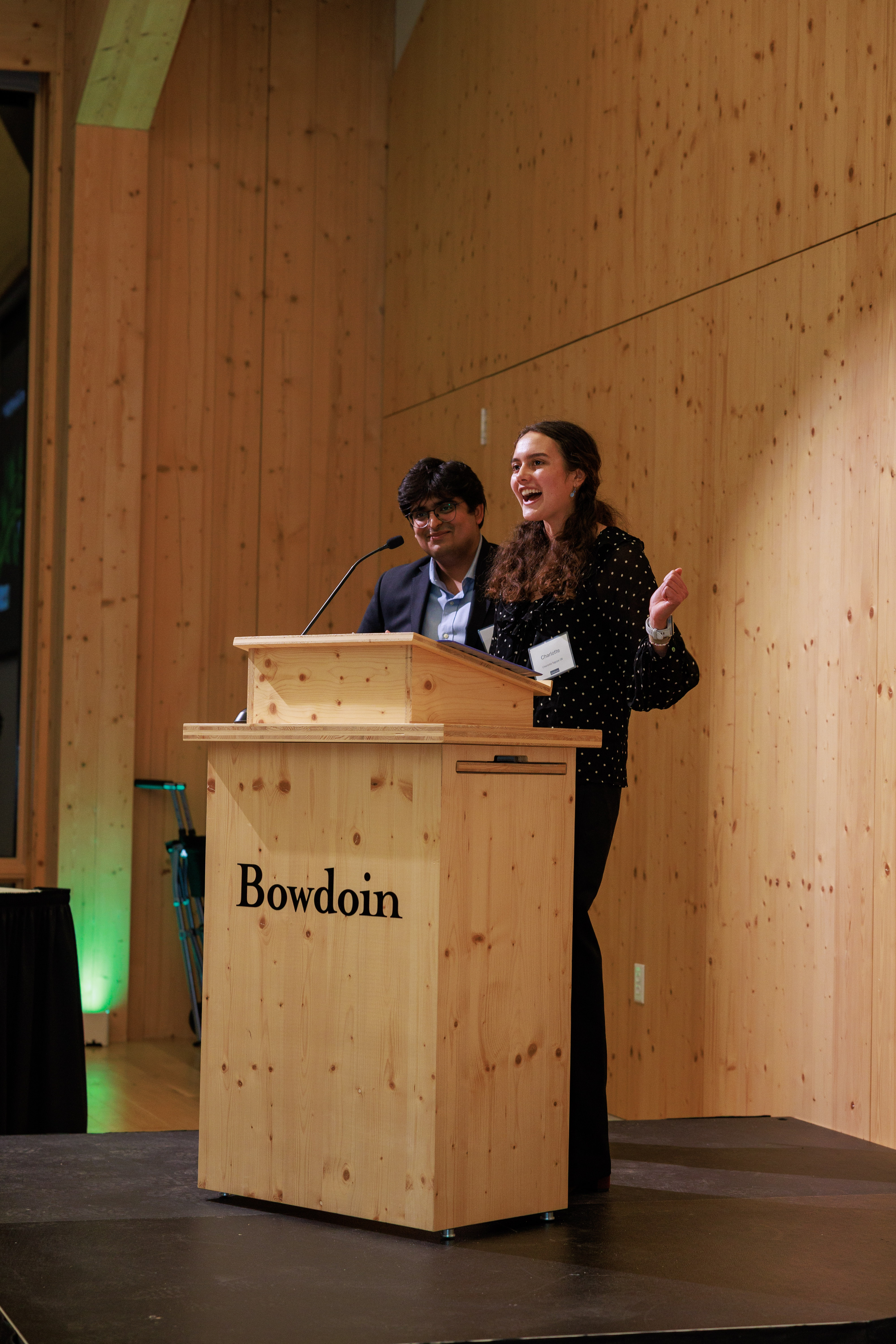 Student leaders Charlotte Tagupa '26 and Pranav Valdamudi '26 speaking at the podium.