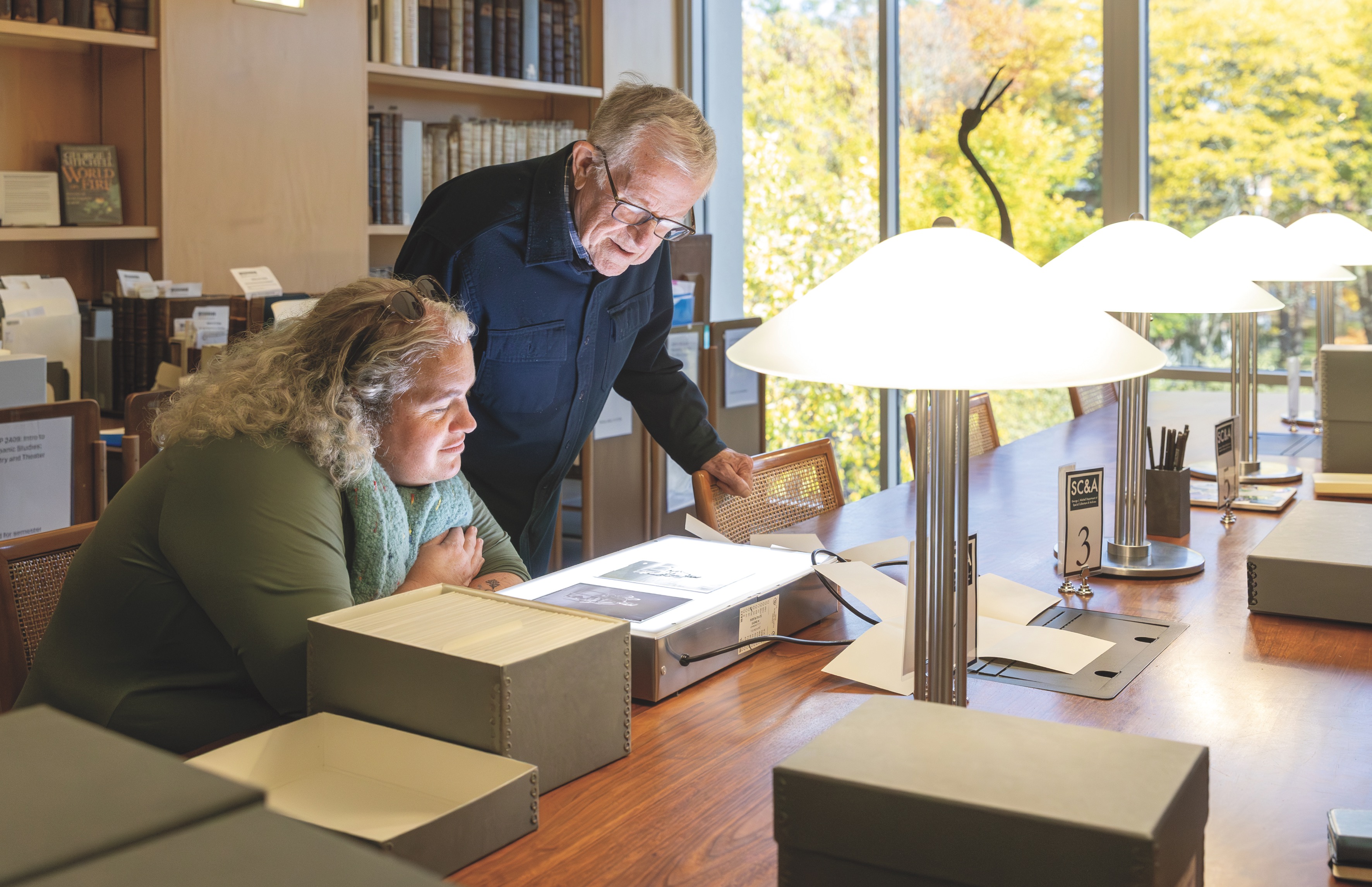 Libby Bischof and Ben Strout examine an object from the collection in the archives reading room.