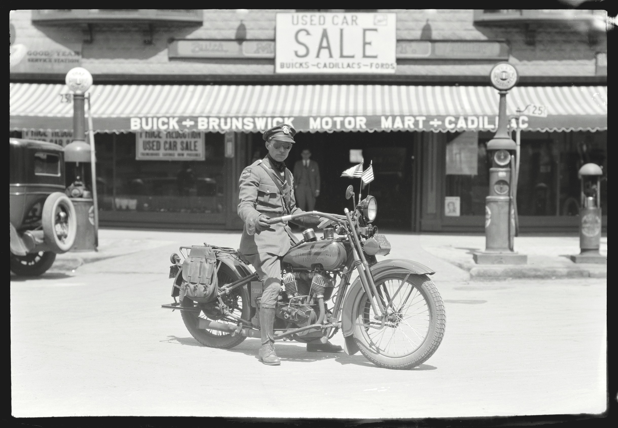 Brunswick police officer on a motorcycle in front of the Brunswick Motor Mart, a building that now houses Bull Moose Music.