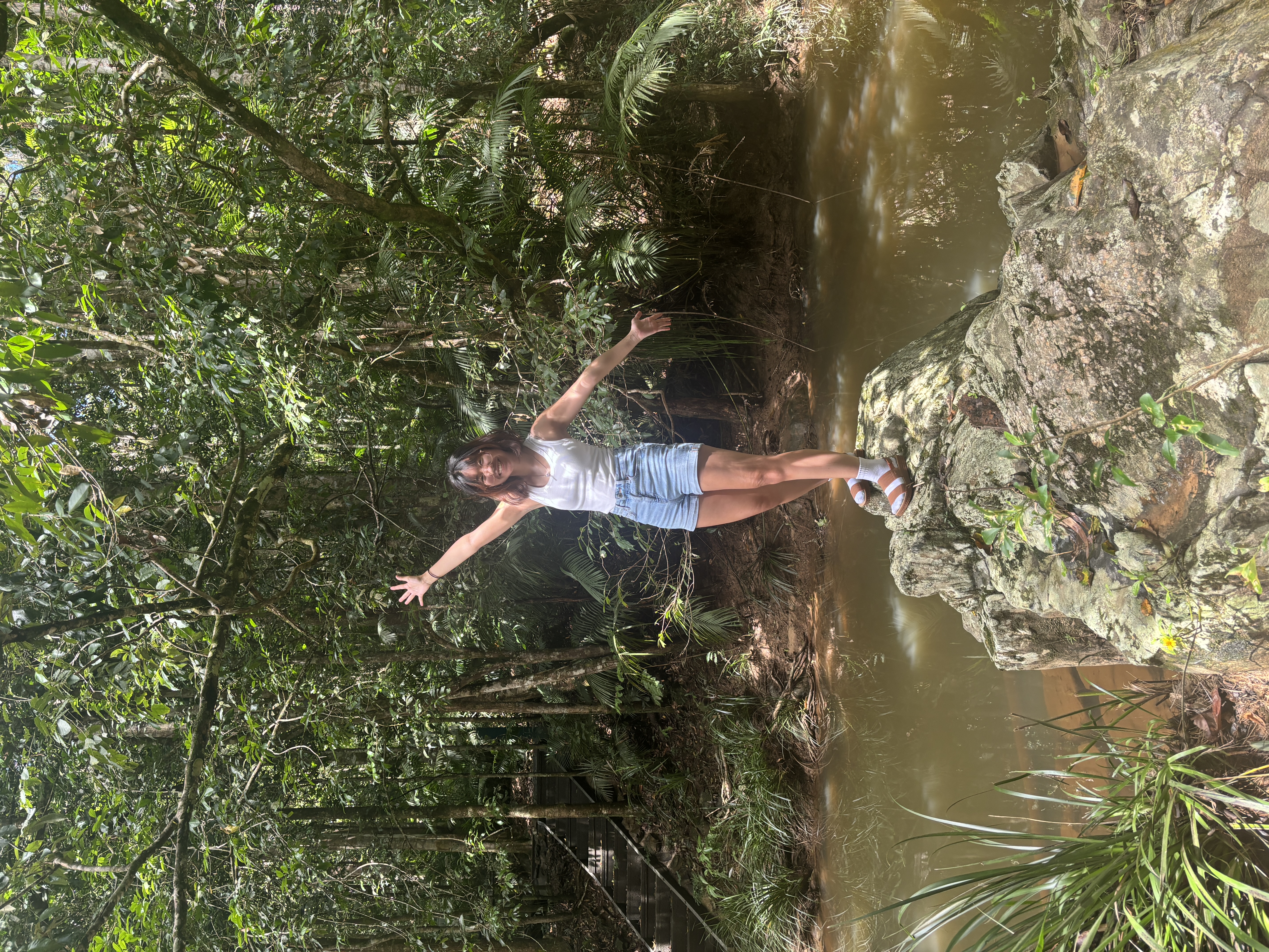 Student standing on rock above pool of water