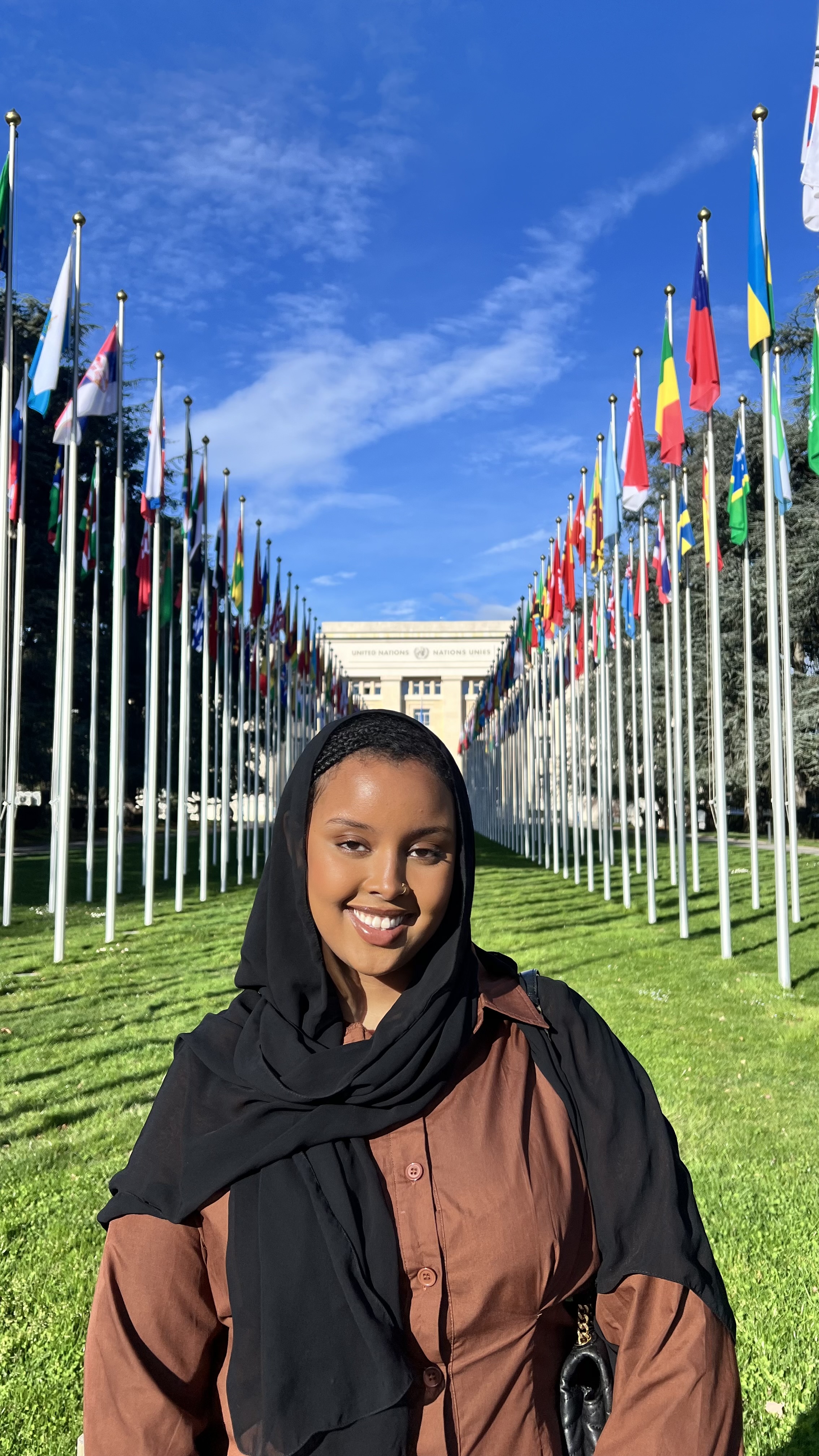 Student standing in front of building with flags.