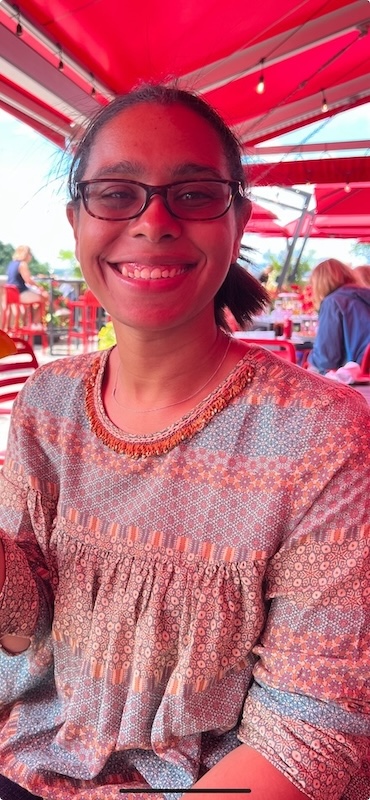 Maya sitting and smiling in an outdoor venue