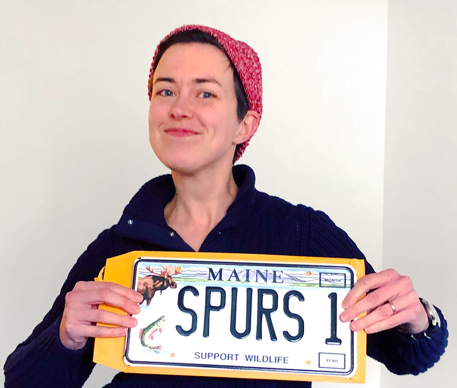 Janie is holding a Maine license plate that says "SPURS 1"
