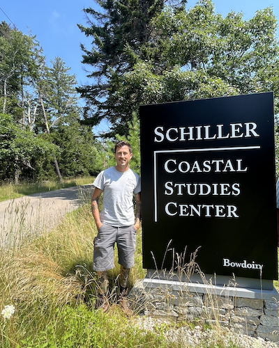Joe Tourelotte standing next to Schiller Coastal Studies Center sign