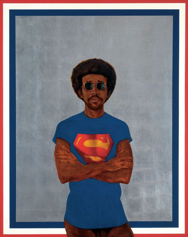 Black man standing with arms crossed, wearing a Superman t-shirt