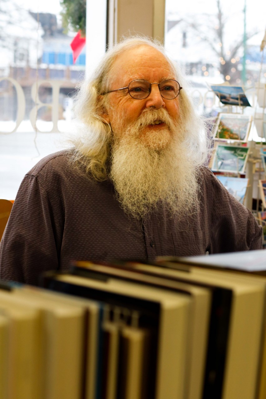 Gulf of Maine Books owner Gary Lawless smiles out over a stack of books