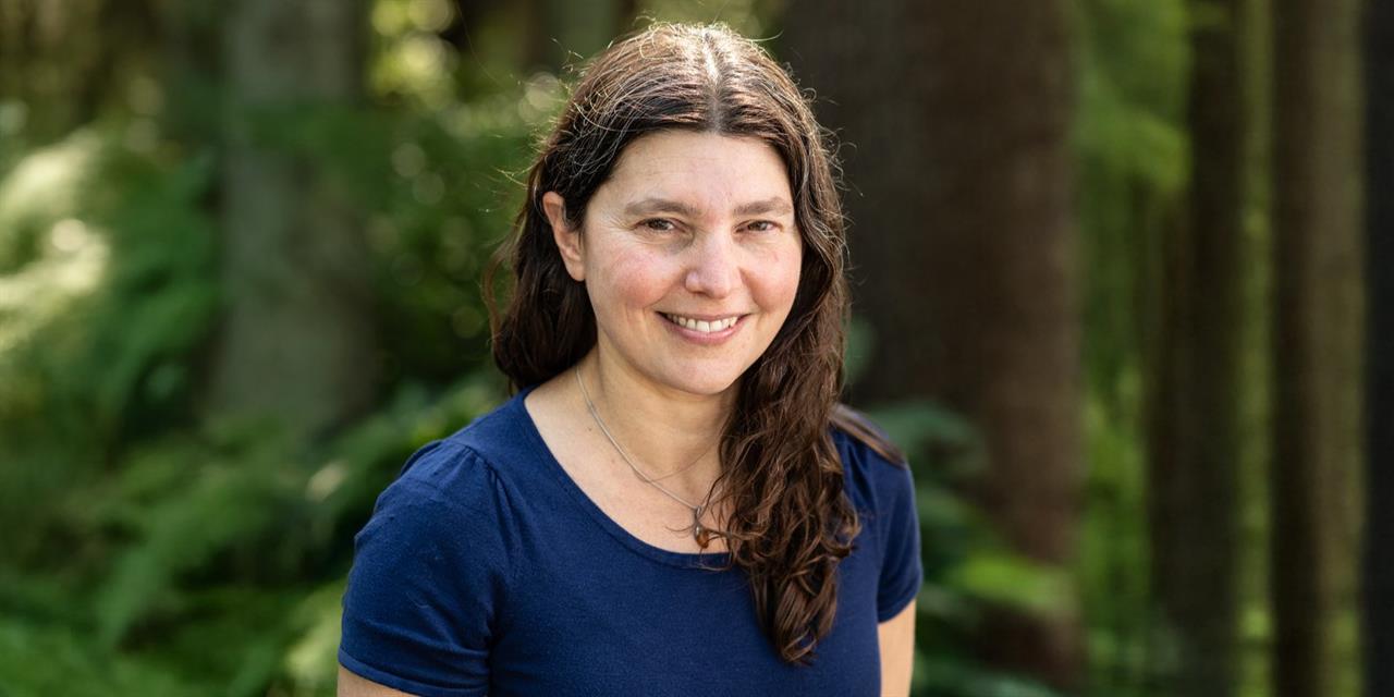 Headshot of Professor Danielle Dube with a forest in the background