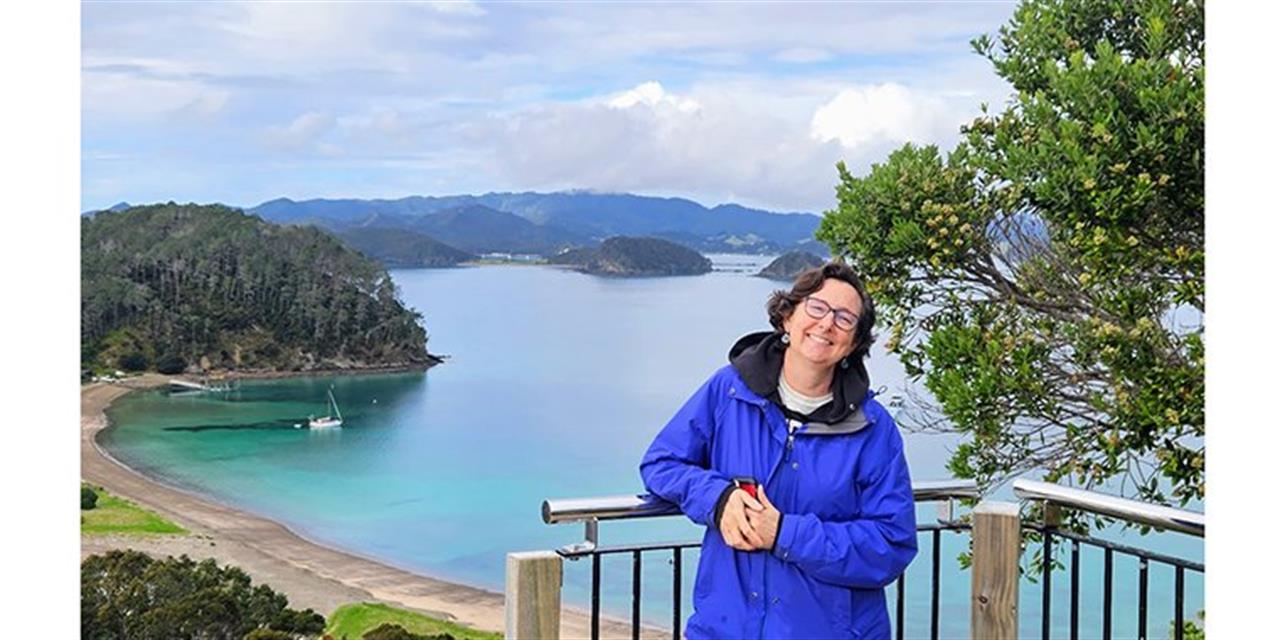 Professor Hadley Horch standing in the foreground with a view of the ocean, beaches, and mountains behind her.