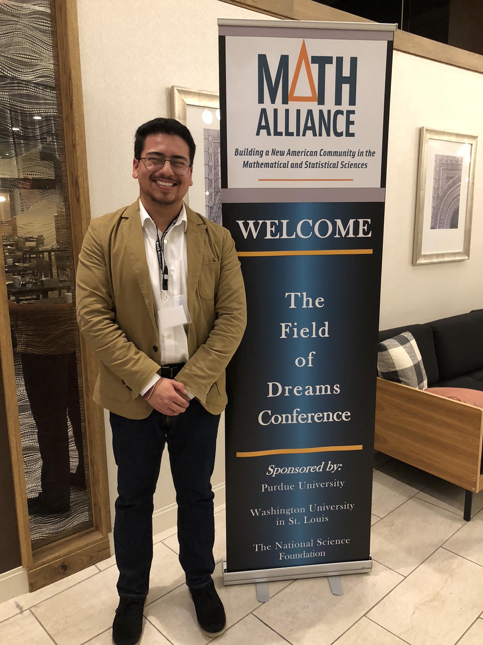 Student standing next to banner at a national conference