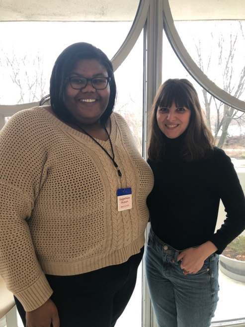 Two women standing next to each other in front of a window